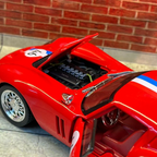 A red die-cast model sports car with its hood and door open, showing a detailed engine bay and interior, set against a brick wall and tiled floor background.