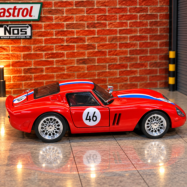 A red die-cast model sports car with blue and white racing stripes, number 46 on the side door, displayed on a tiled floor in front of a brick wall backdrop with automotive-themed wall decals.